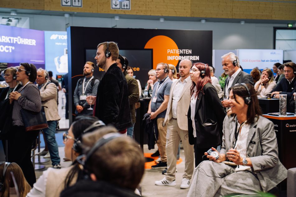 Publikum mit Kopfhörern die der Boothlecture am 1stQ Stand auf der DOC 2025 zuhören